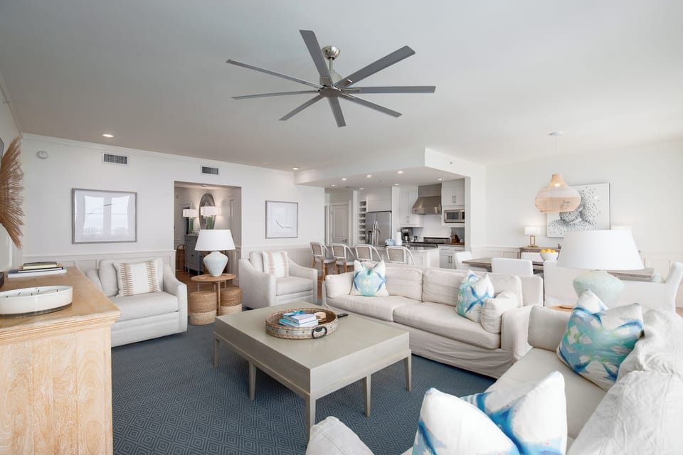 Sink into plush sofas with ocean-inspired pillows in this bright, open living space where coastal elegance meets modern comfort.