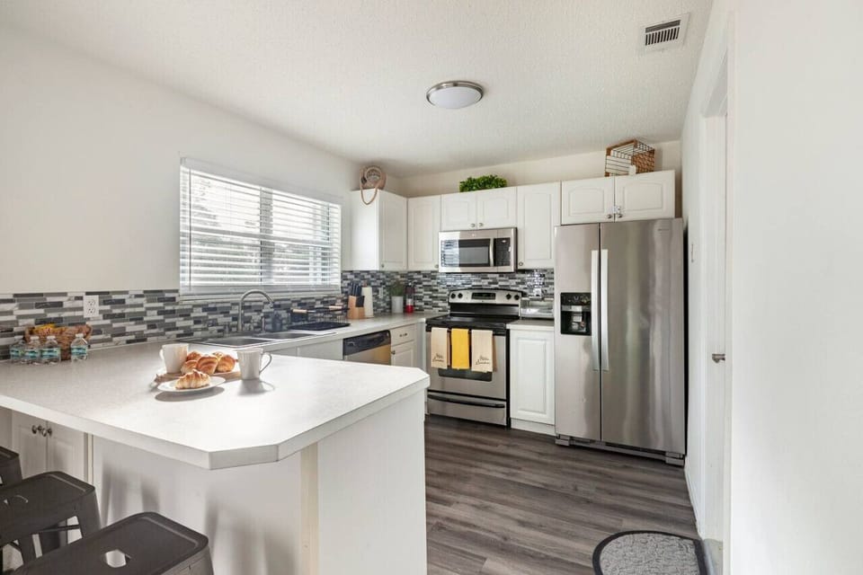 Modern kitchen with stainless steel appliances, bright light, and cozy breakfast bar.