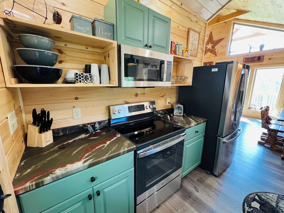 Modern kitchen with full-size stainless steel refrigerator, stove, and over-the-range microwave at A Tyme to Chill cabin in Wears Valley, Tennessee.