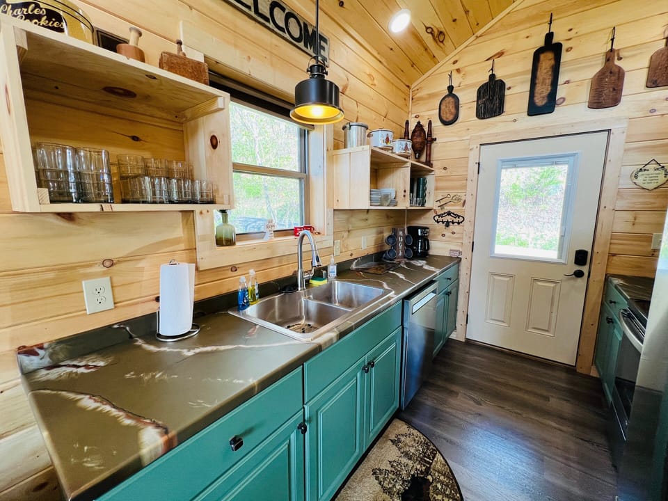 Fully equipped kitchen with teal cabinetry, sink, stove, microwave, dishwasher, and coffee maker at A Tyme to Chill cabin in Wears Valley, Tennessee.