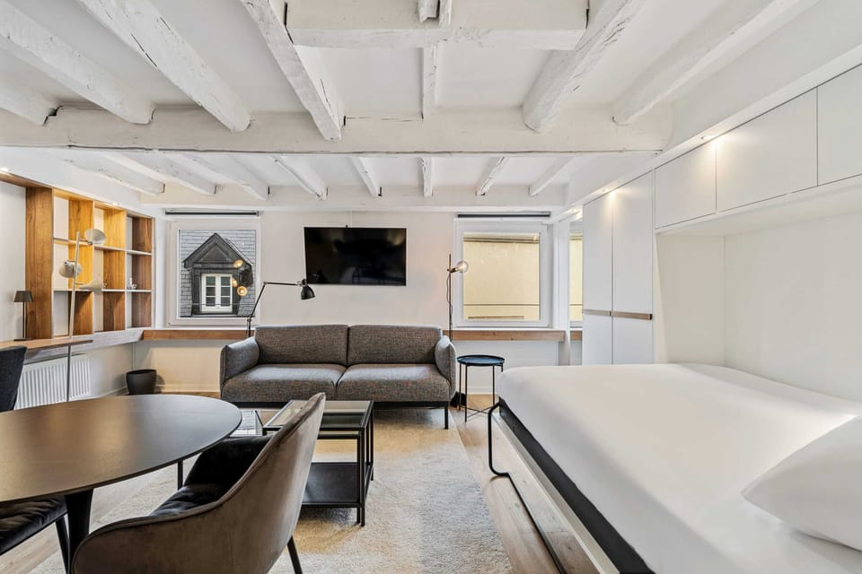 Open-concept living area with a comfortable couch, flat-screen TV, and large windows for natural light.