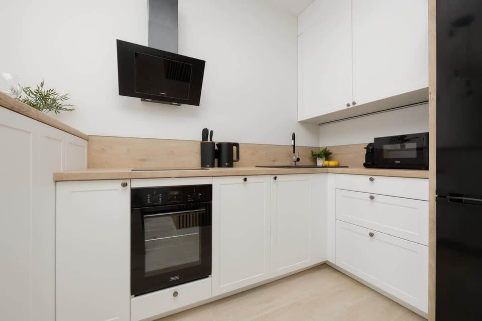 A bright and modern kitchen with white cabinetry, black accents, and built-in appliances. Functional and stylish, perfect for home-cooked meals.