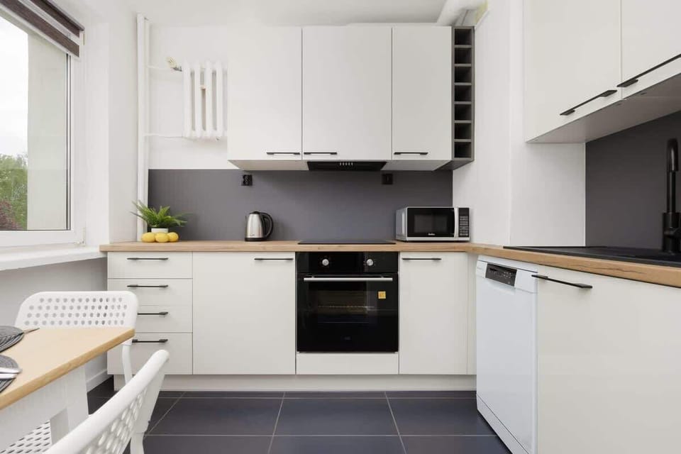 A fully equipped kitchen with white cabinetry, built-in oven, and black countertop. The space is compact yet functional for meal preparation.