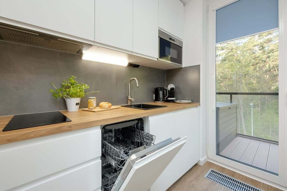 Kitchen with white furniture and wooden worktop. Appliances such as a dishwasher and microwave oven make it easy to prepare home-cooked meals. 