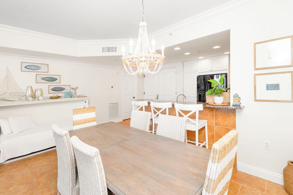 Gather around your elegant dining table under a stunning white chandelier, while the open kitchen invites you to cook together in this coastal-inspired space.