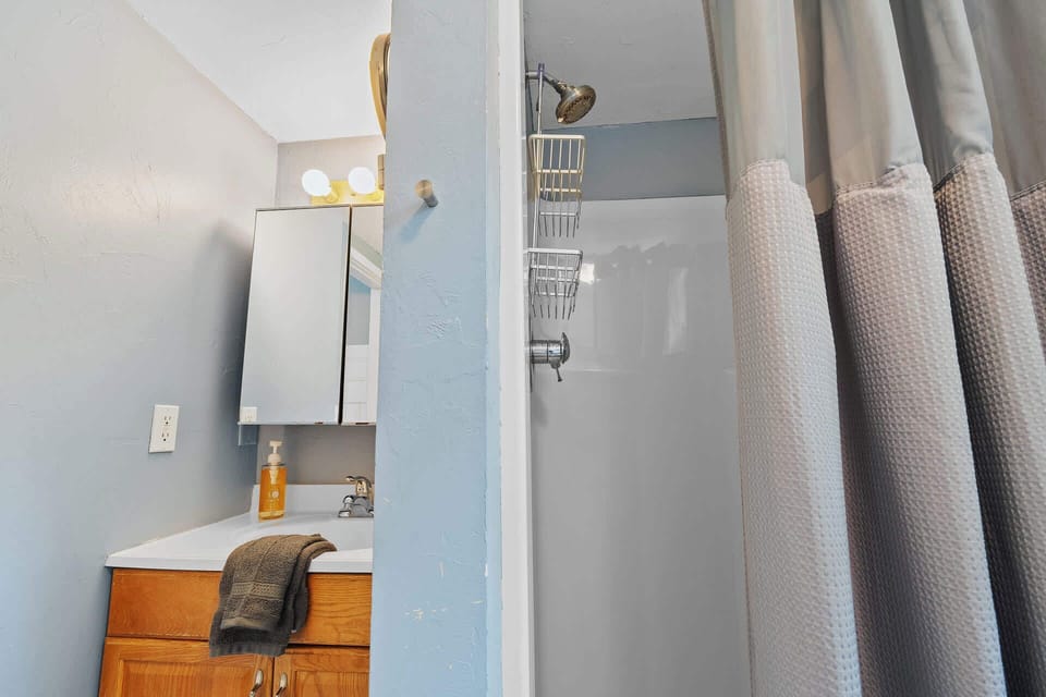 Step into your refreshed bathroom featuring a clean walk-in shower and vanity area, ready for your stay.