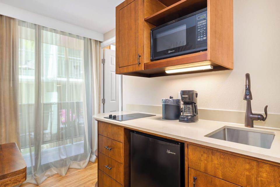Your compact kitchenette features modern appliances, warm wood cabinetry, and everything you need to prepare light meals during your stay.