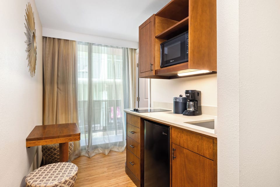 Your compact kitchenette features modern appliances including a microwave, coffee maker, mini-fridge, and cooktop—everything you need to prepare light meals in the comfort of your suite.
