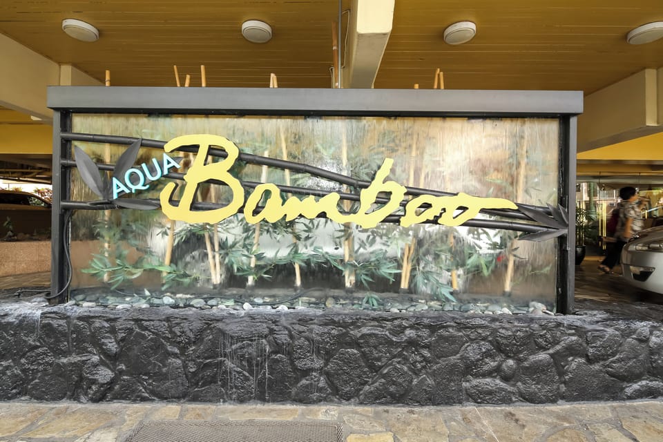 Aqua Bamboo property signage with decorative water feature at the entrance, displaying the property branding and welcoming ambiance.