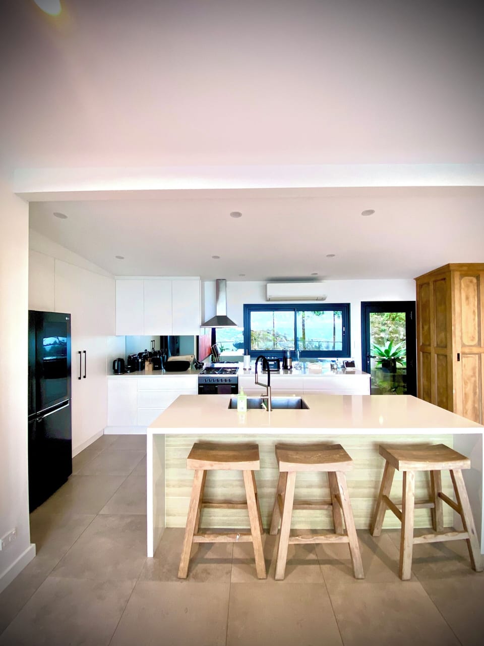 Island bench with large wooden stools in the entertainers kitchen