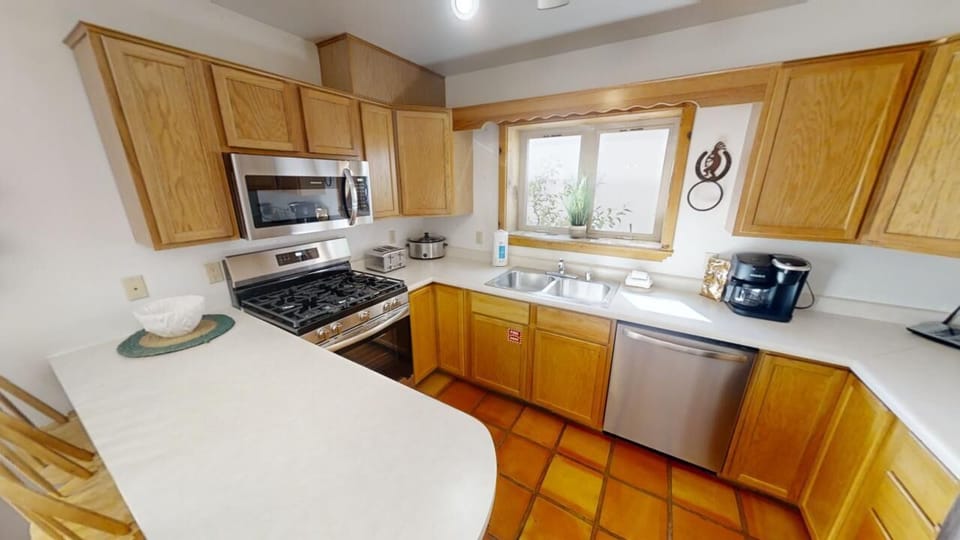 Your fully equipped kitchen features warm oak cabinetry, stainless steel appliances, and charming terracotta tile floors—perfect for preparing home-cooked meals during your stay.