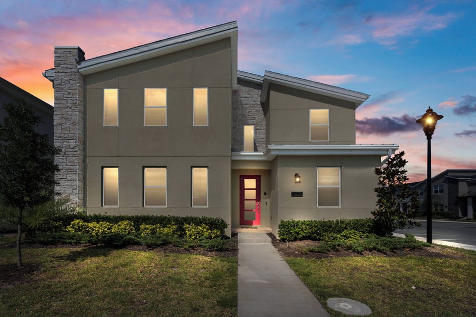 Welcome to this stunning home with a modern design and a charming red door. The softly lit windows create a warm atmosphere, ideal for relaxing evenings in the beautifully landscaped garden.