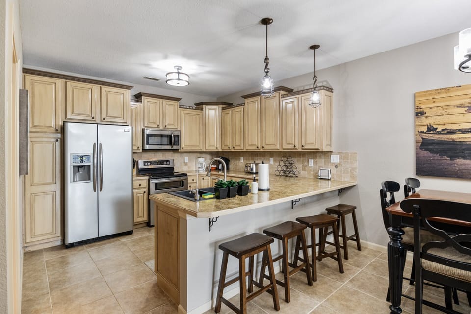 Spacious and fully-equipped kitchen with modern stainless steel appliances, ample counter space, and a breakfast bar with seating for casual dining.