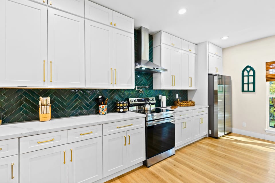 At the heart of the Black House lies a stunning chef’s kitchen, highlighted by a dramatic 6-foot waterfall island, built-in wine fridge, custom cabinetry, and a charming farmhouse sink