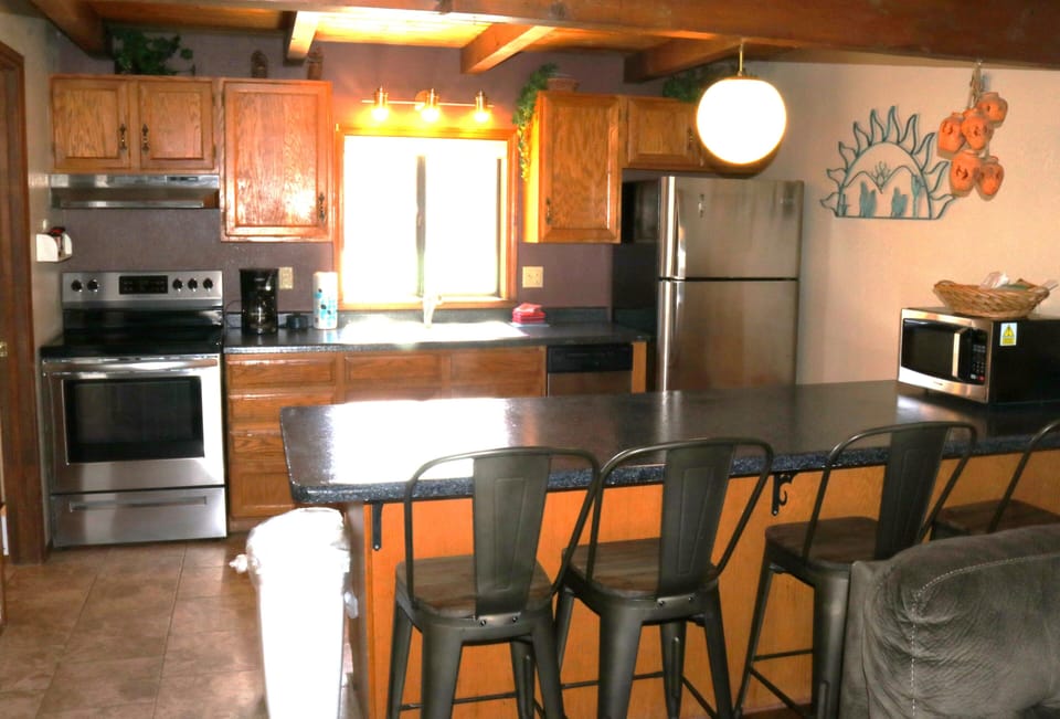 Gather around your fully equipped kitchen island with modern appliances, warm wood cabinetry, and cheerful orange accents inviting you to cook memorable meals together.