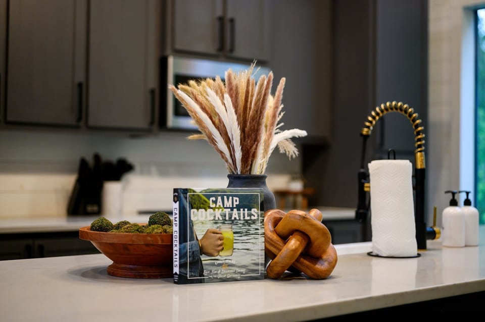 - Thoughtful touches like a cocktail book, moss bowl, and pampas vase style the island - Golden faucet and paper towel station provide function without compromising charm - Cozy balance of cabin vibes and upscale modern kitchen design