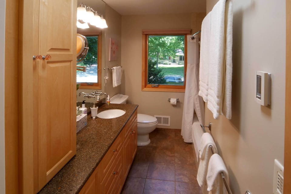 Luxury bathroom with heated floor, soaking tub, and quartz countertop.