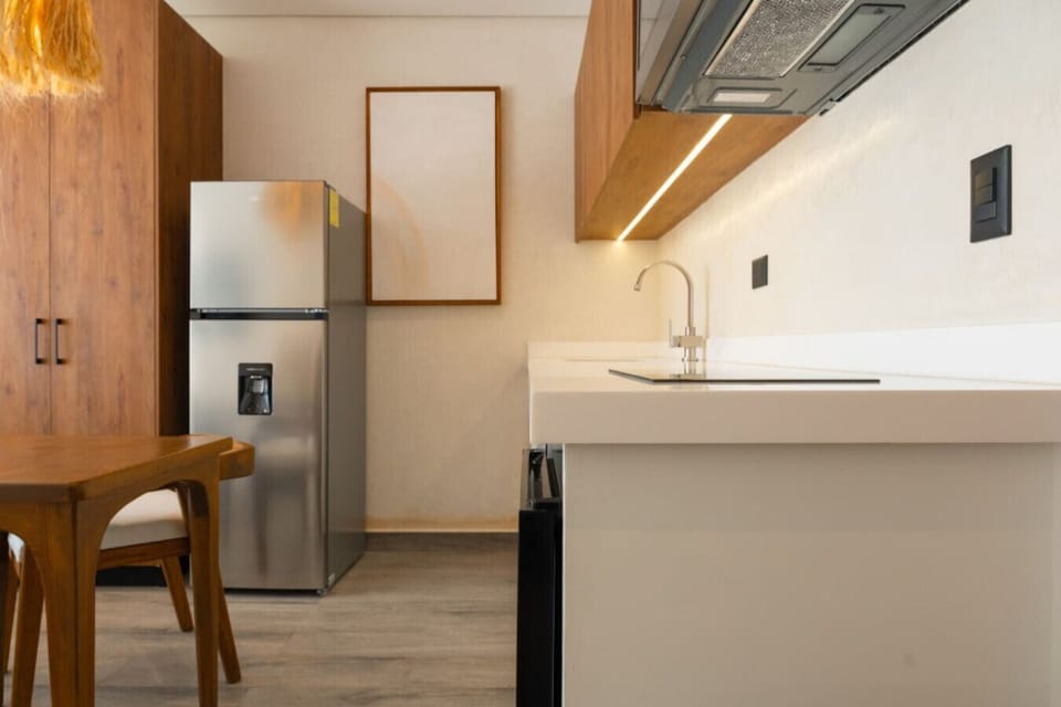 Modern kitchen with fridge, cooktop, and wood accents.