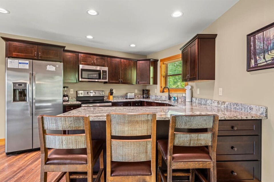 Pull up a chair and start the day with coffee at the granite island. With rich wood cabinetry and stainless appliances, this kitchen is designed for easy mornings and shared meals.
