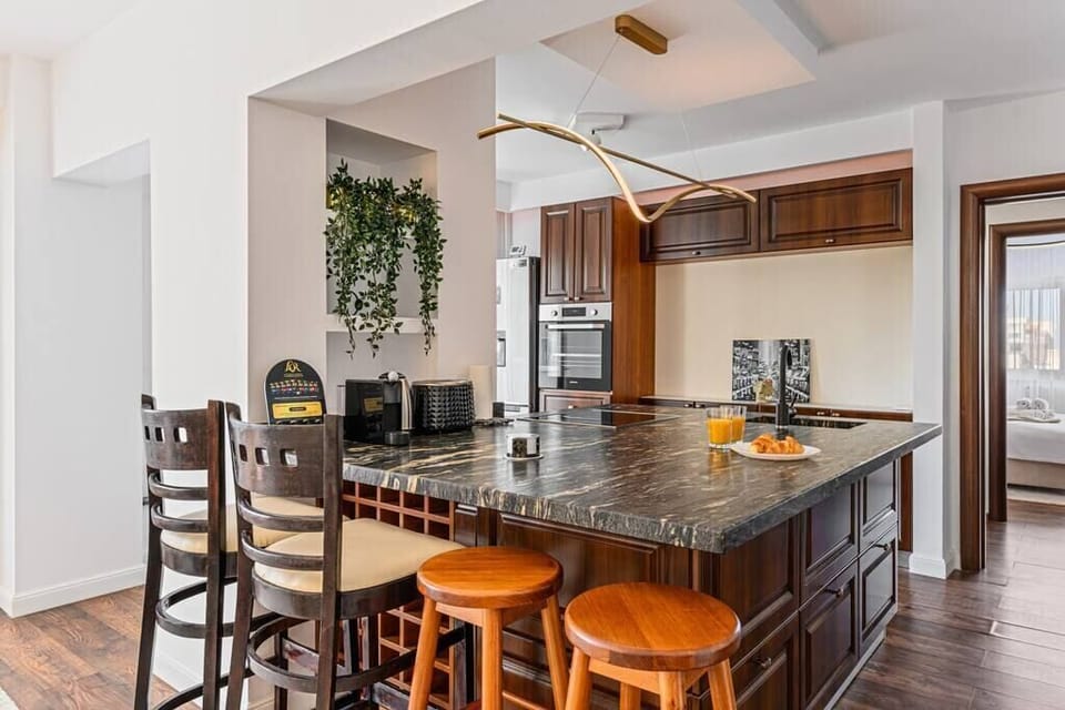 Open space kitchen equipped with table and chairs for dining, toaster, coffee machine + capsules, kettle, oven and stove + refrigerator with freezer 