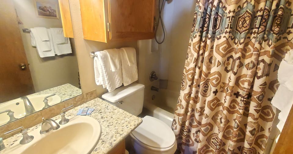 Freshen up in your private bathroom featuring a tub-shower combo, stylish patterned curtain, and all the essentials you need for a comfortable stay.