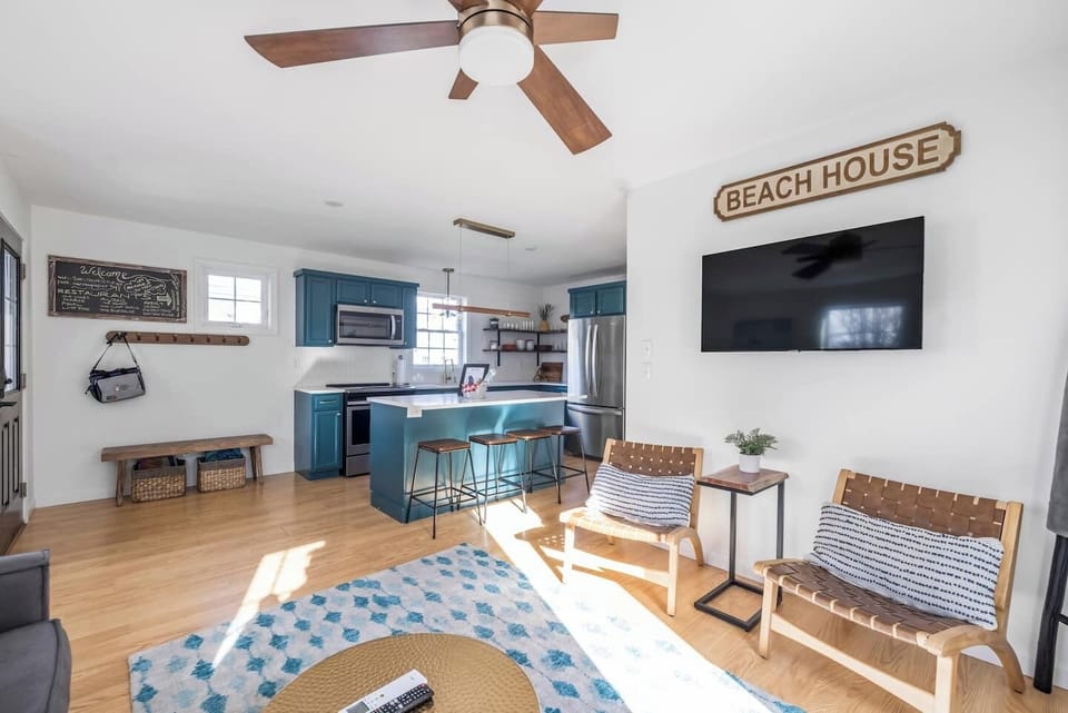 Light-filled beach-inspired living area with cozy seating, smart TV, and a stylish kitchen perfect for gathering.