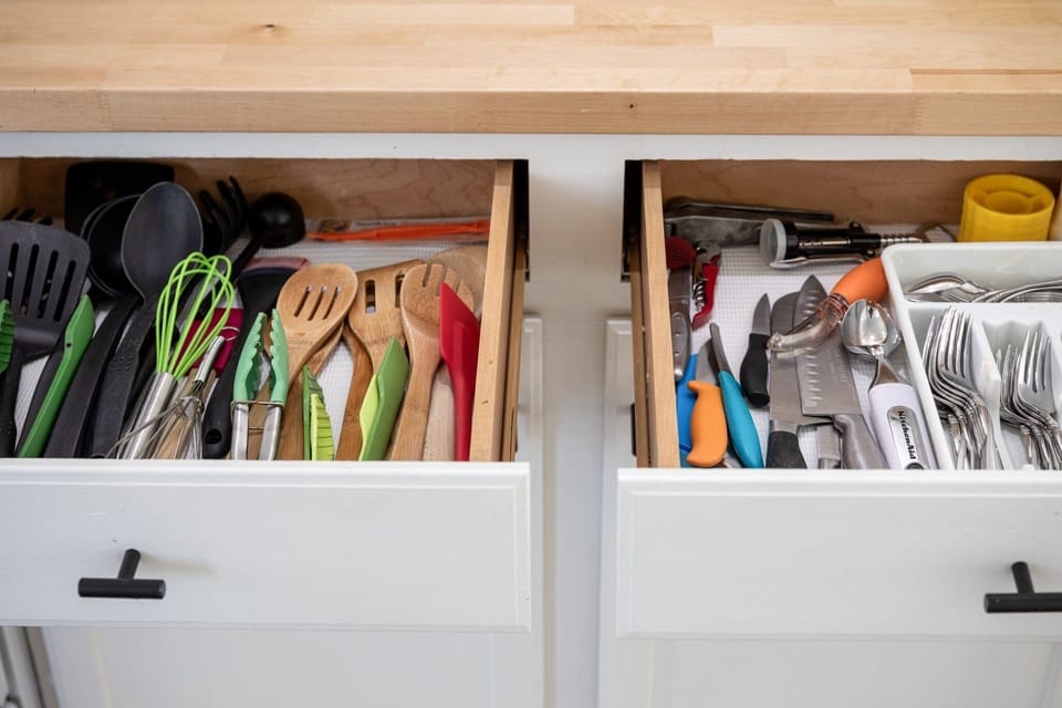 Kitchen drawers, one housing cooking utensils and the other storing cutlery, display an array of tools, all poised and ready for your culinary endeavors.