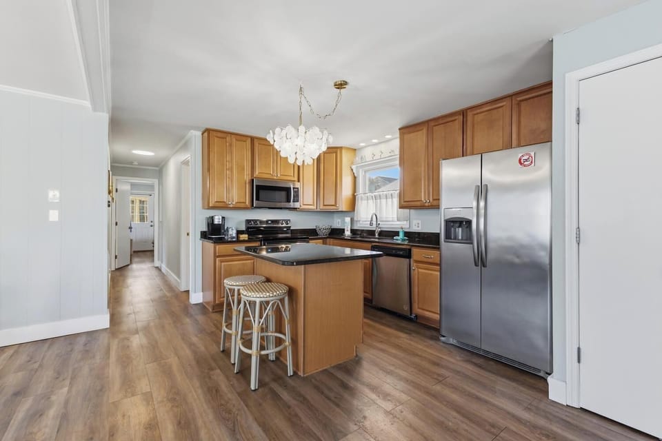 Step into your bright, fully-equipped kitchen where you'll find sleek stainless steel appliances, warm wood cabinetry, and a convenient island perfect for morning coffee or meal prep.