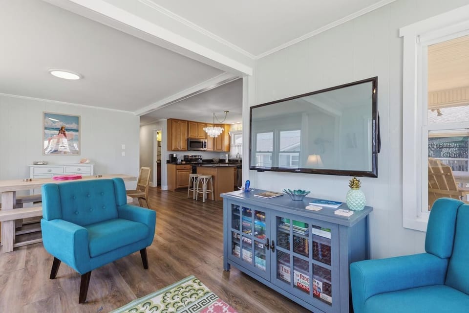 Step into your bright, open living space where coastal charm meets modern comfort. Sink into vibrant turquoise chairs, unwind with your favorite shows on the flat-screen, and feel right at home in this inviting retreat.