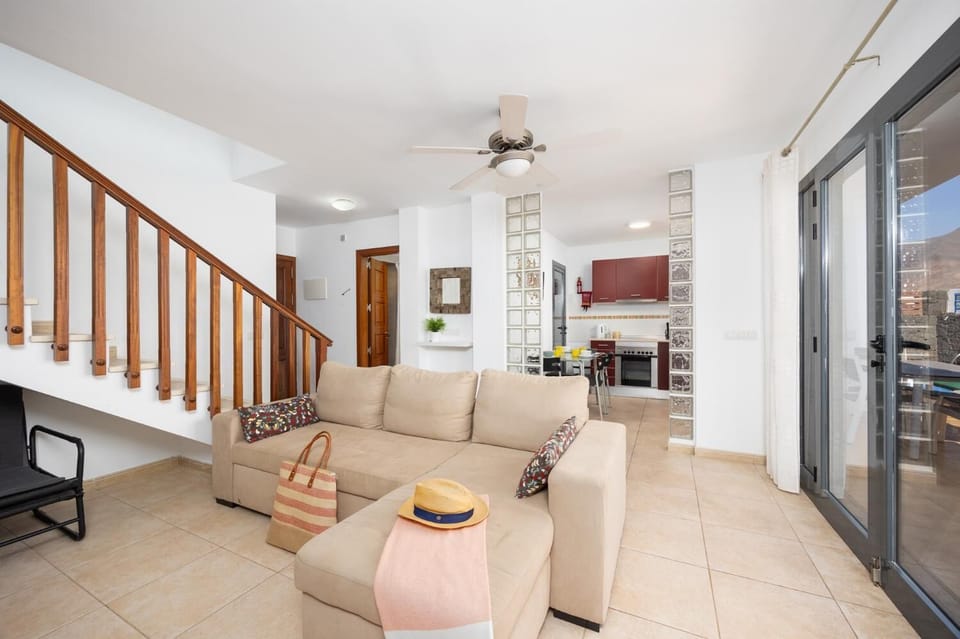 Open-plan living room with sofa, dining area, kitchen, A/C, WiFi internet, and satellite TV