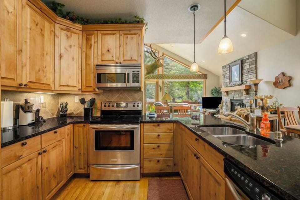 Elk River Cabin Kitchen with glass top electric stove/oven, with microwave range hood, and sink in the kitchen peninsula. 