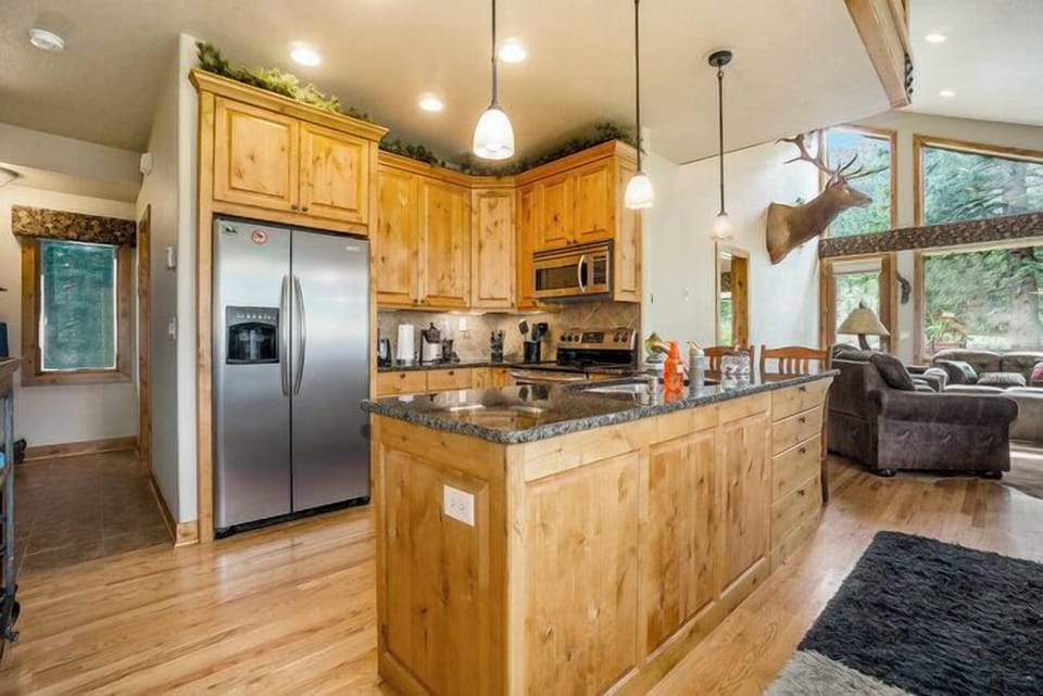 Elk River Cabin Kitchen with refrigerator, stove/oven with microwave range hood, and peninsula with sink.