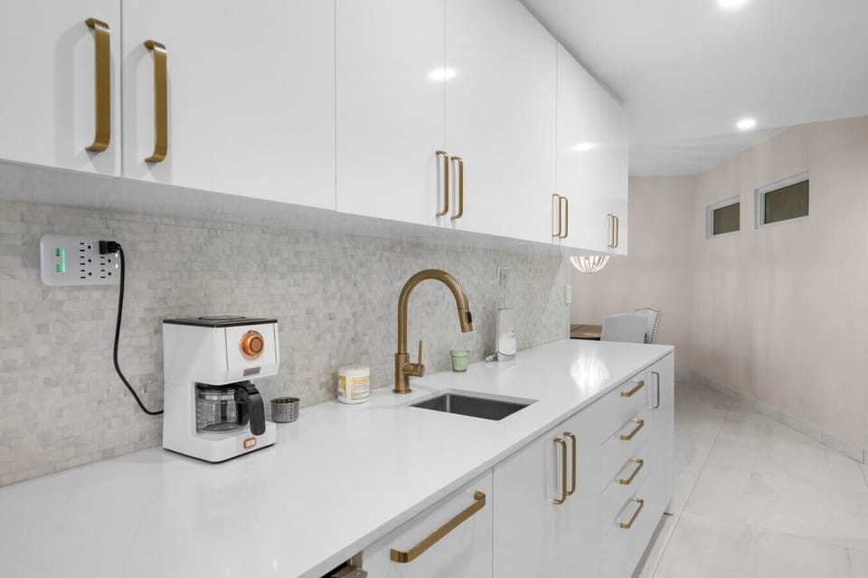 Fully equipped kitchen  with coffee maker, sink, and gold hardware