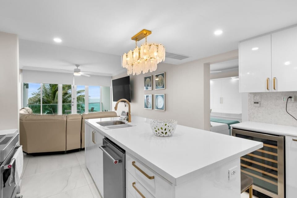 Open-concept kitchen island with wine cooler flowing into ocean-view living area