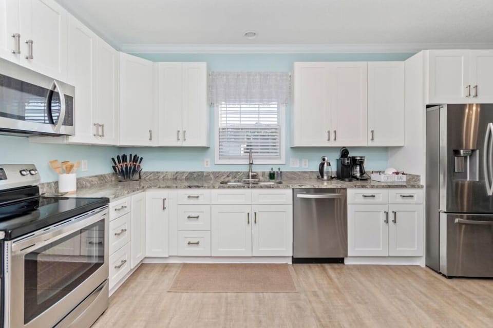 Modern kitchen with essential appliances, indoor grill, raclette, and coffee bar.