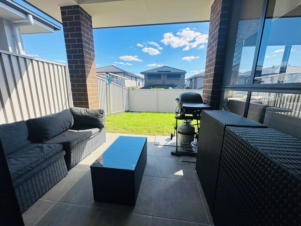 Large patio with seating, lawn, BBQ and fan