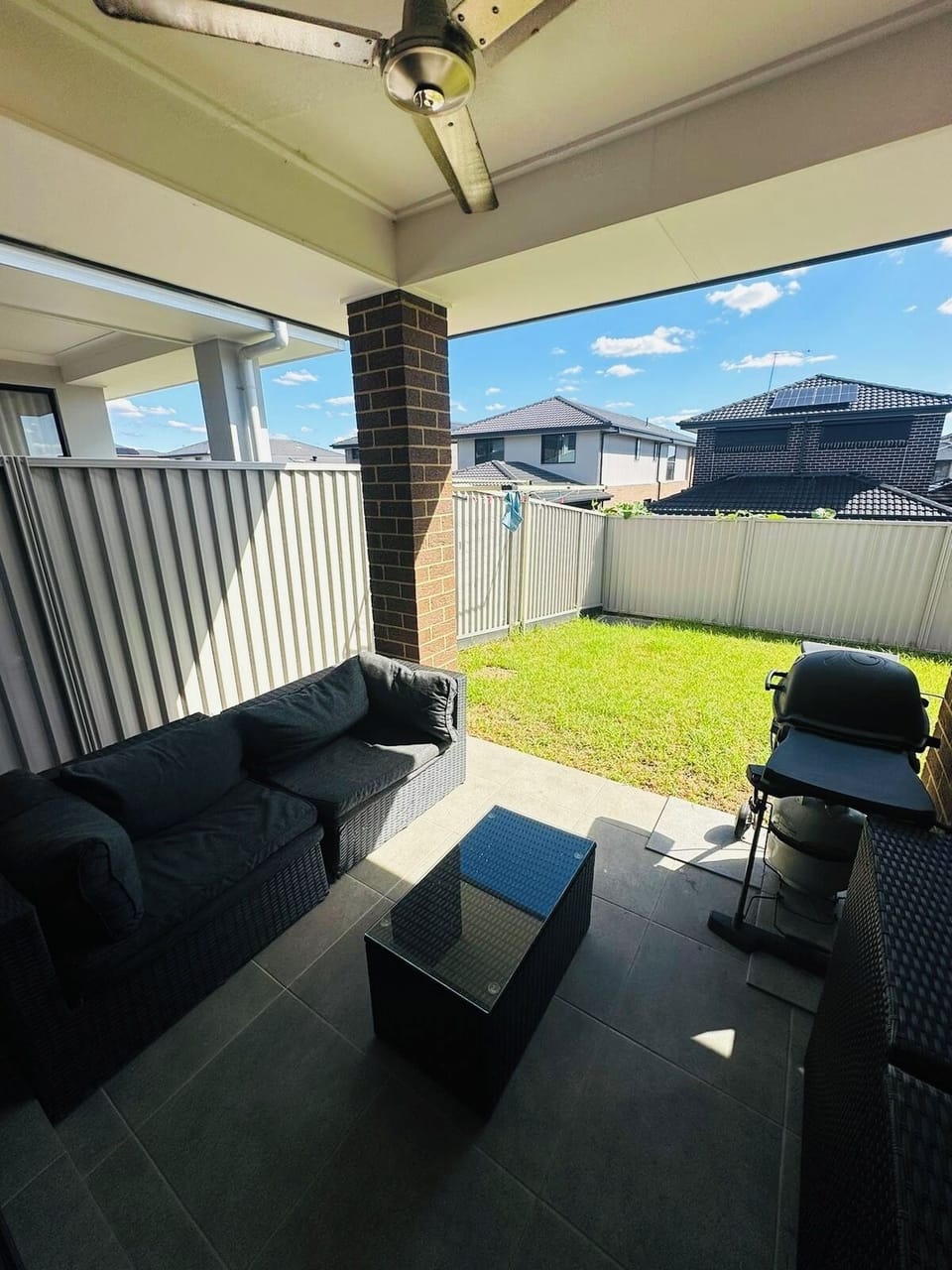 Large patio with seating, lawn, BBQ and fan