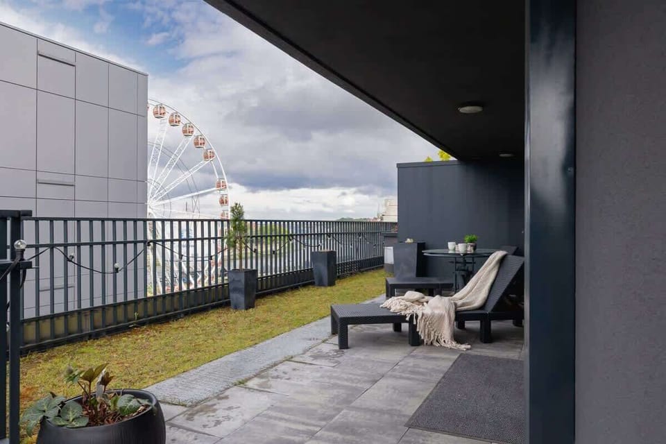 Another balcony space with two chairs and a small table, framed by metal railings.


