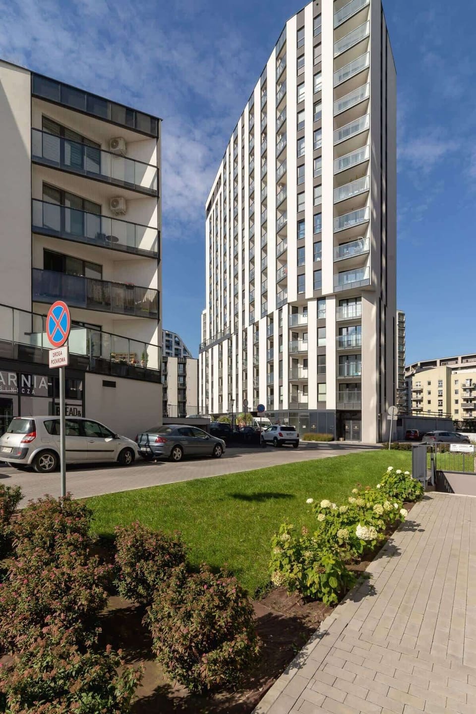 Exterior view of a contemporary apartment building with clean lines and a pedestrian walkway.


