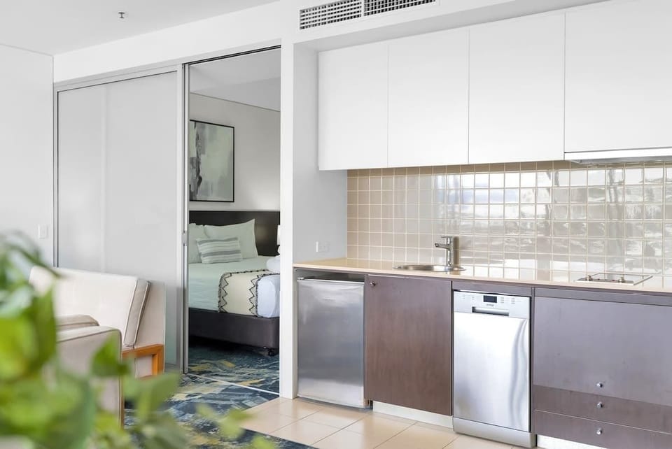 The kitchenette is equipped with a dishwasher, ceramic hot plates, and a small fridge, making meal prep a breeze.

