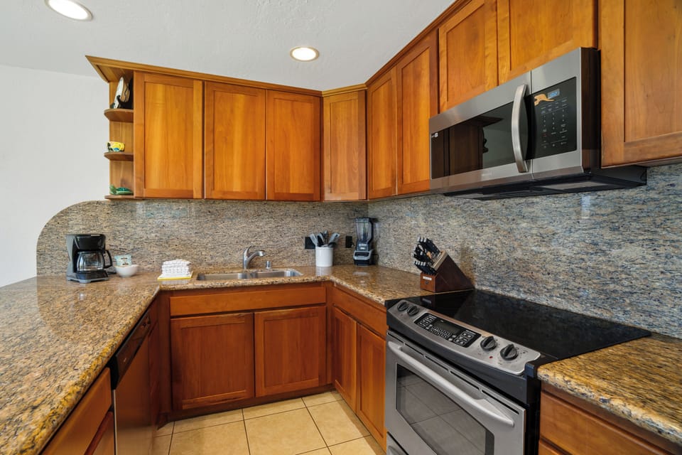 Step into your fully-equipped kitchen with warm wood cabinetry and gleaming granite countertops, ready for preparing your favorite vacation meals with ease and comfort.
