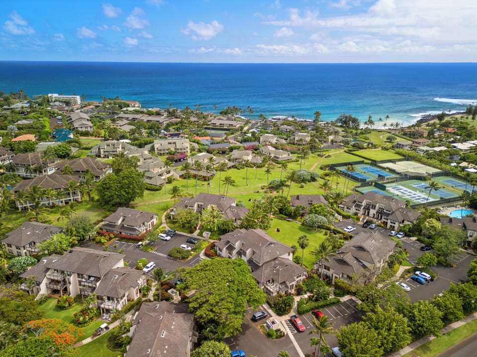 Beachfront resort complex featuring tennis courts, lush tropical landscaping, and direct access to pristine turquoise waters and sandy shores.