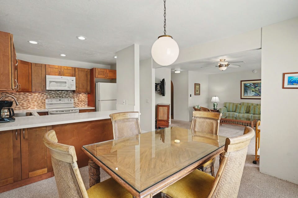 Gather around this elegant dining table with tropical artwork adorning the walls, while the fully-equipped kitchen invites you to prepare your favorite meals in comfort.
