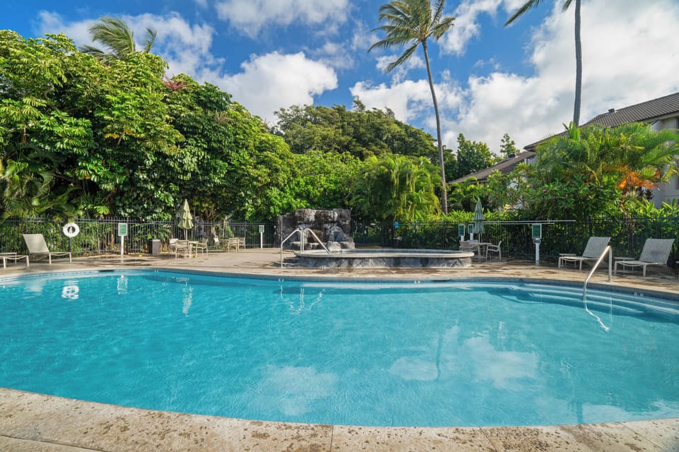 A sparkling tropical pool surrounded by lush palms and loungers, perfect for soaking up the sun and cooling off during your island getaway.
