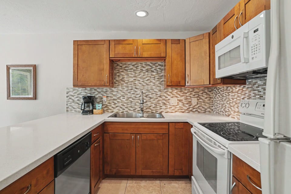 Your fully equipped kitchen features warm wood cabinetry, modern appliances, and stylish mosaic tile backsplash, making meal prep a pleasure during your stay.