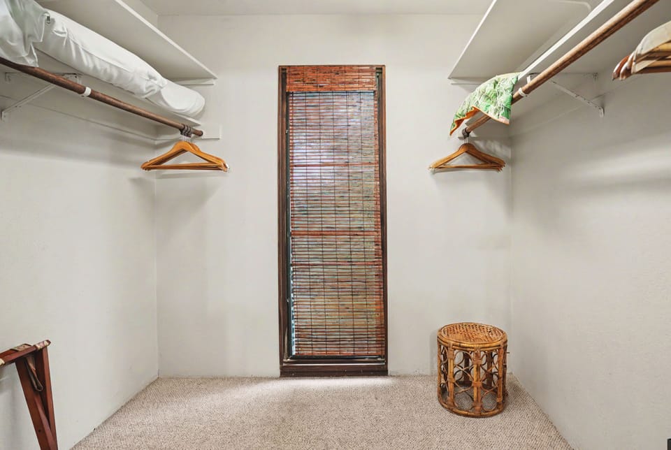 Your private walk-in closet offers generous hanging space on both sides, a charming bamboo window for natural light, and a wicker stool—perfect for organizing your wardrobe in comfort.