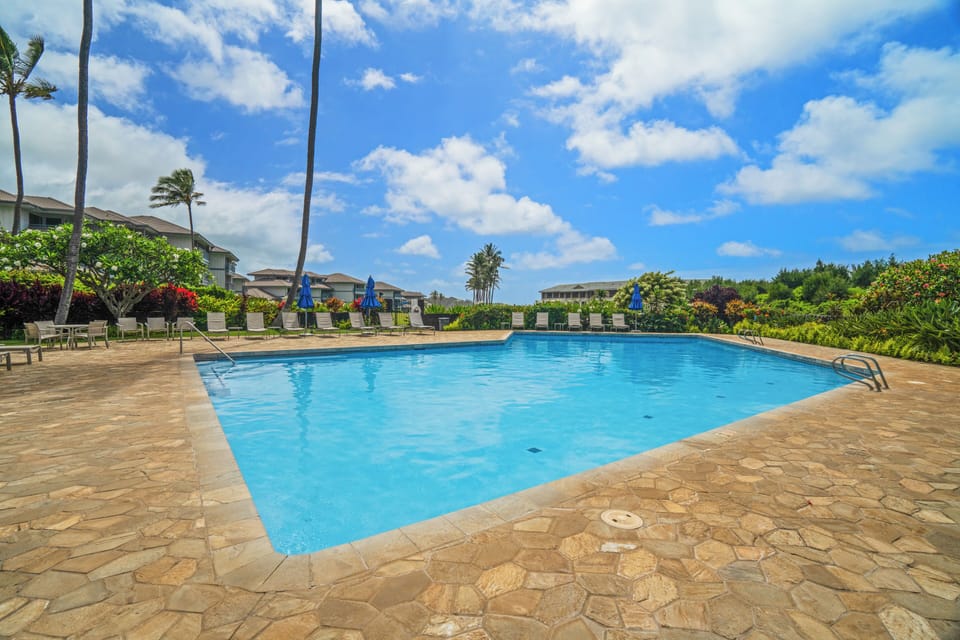 A sparkling pool set against swaying palms and lush tropical landscaping, perfect for cooling off under the warm Hawaiian sun.