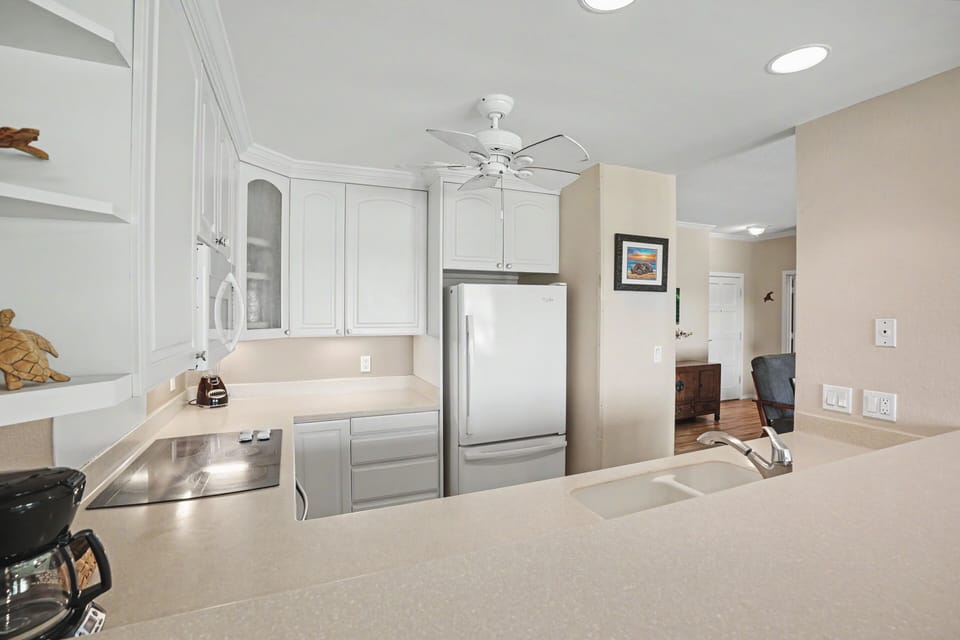 Your fully equipped kitchen features bright white cabinetry, modern appliances, and plenty of counter space—perfect for preparing meals in coastal comfort.