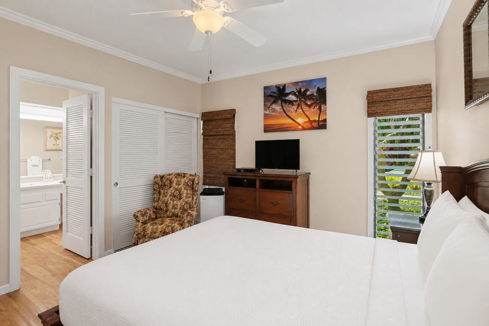 Unwind in your peaceful bedroom, complete with plush bedding, tropical sunset artwork, and entertainment. Your ensuite awaits through the louvered door.