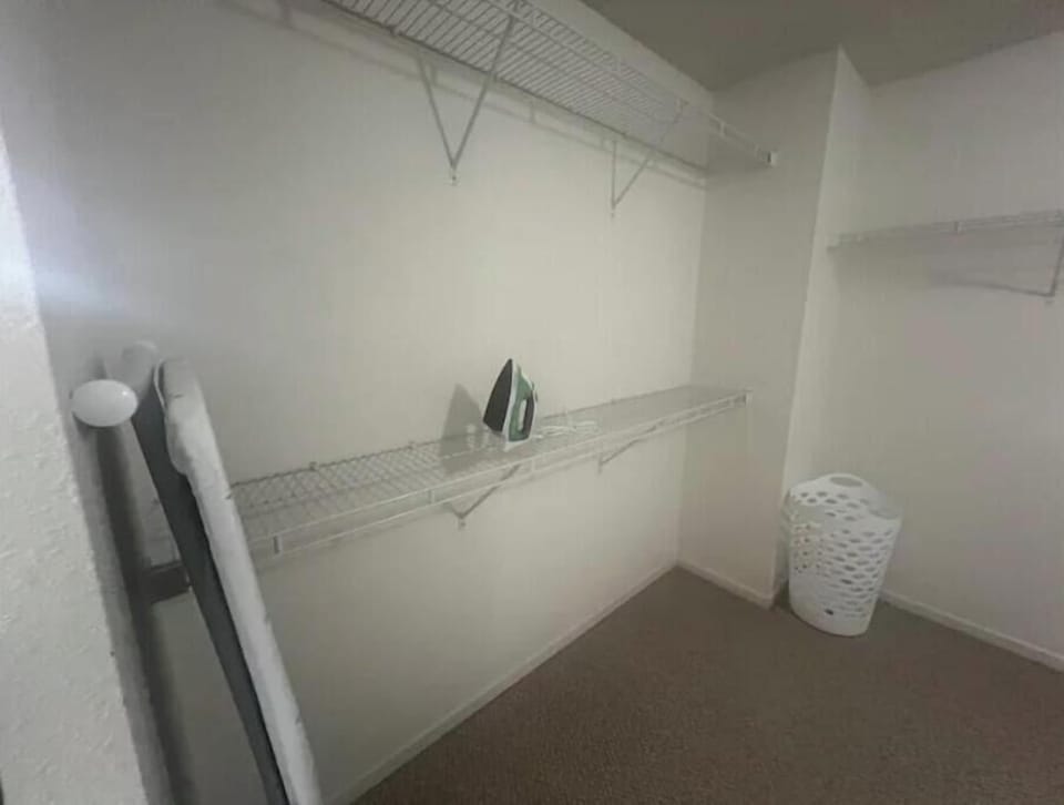 Spacious walk-in closet with pack ’n play, iron, and ironing board.